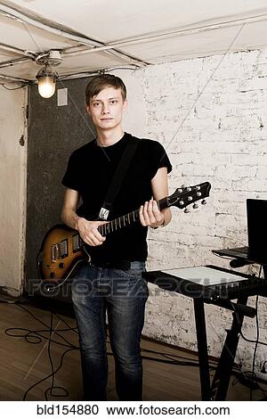 Stock Image - Caucasian man playing electric guitar in rock band. Fotosearch
