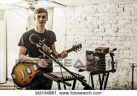 Stock Image - Caucasian man playing electric guitar in rock band. Fotosearch
