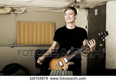 Stock Photo - Caucasian man playing electric guitar in rock band. Fotosearch