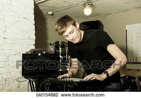 Stock Image - Caucasian man playing synthesizer in rock band. Fotosearch
