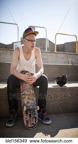 Stock Photo - Caucasian man sitting at skate park. Fotosearch