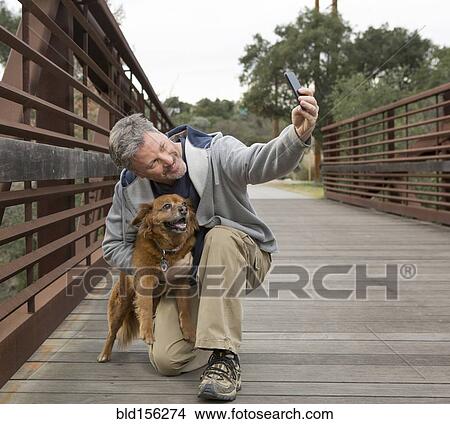 Caucasian man taking photograph with dog on bridge View Large Photo Image Picture - Caucasian man taking photograph with dog on bridge. Fotosearch