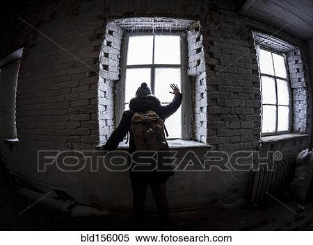Stock Photography - Caucasian man waving through illuminated window at night. Fotosearch