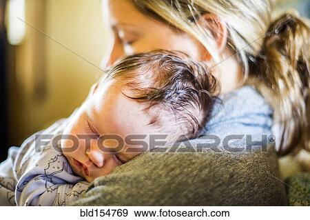 Stock Photo - Caucasian mother holding sleeping baby son. Fotosearch