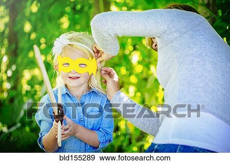 Caucasian mother tying mask on daughter View Large Photo Image Stock Photo - Caucasian mother tying mask on daughter. Fotosearch