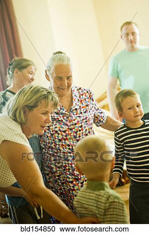 Stock Image - Caucasian multi-generation family relaxing indoors. Fotosearch