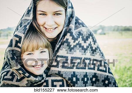 Caucasian sisters wrapped in blanket on farm View Large Photo Image Stock Photo - Caucasian sisters wrapped in blanket on farm. Fotosearch
