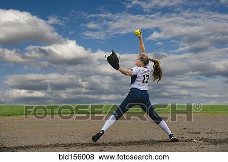 Stock Photo - Caucasian softball player pitching ball in field. Fotosearch