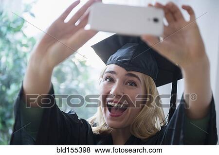 Caucasian student taking cell phone photograph at graduation View Large Photo Image Stock Photo - Caucasian student taking cell phone photograph at graduation. Fotosearch