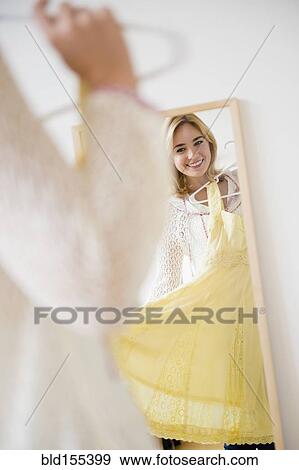 Stock Photo - Caucasian woman admiring dress in mirror. Fotosearch