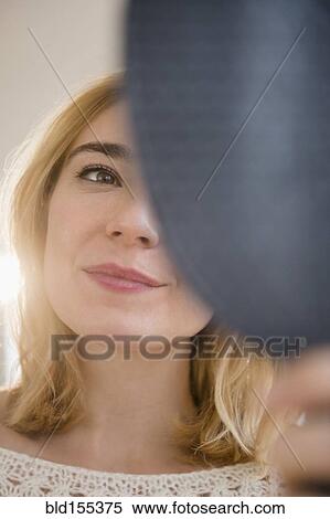 Stock Photography - Caucasian woman admiring herself in mirror. Fotosearch