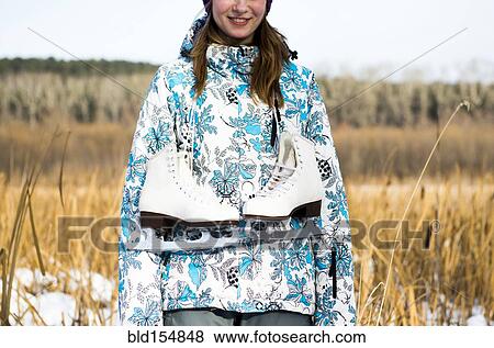 Stock Photo - Caucasian woman carrying ice skates in field. Fotosearch