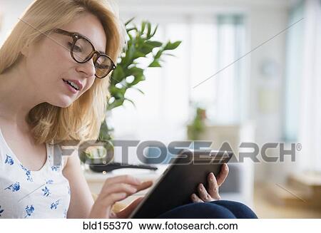 Stock Image - Caucasian woman in eyeglasses using digital tablet. Fotosearch