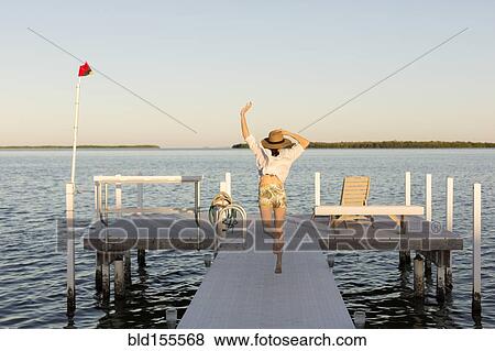 Stock Photo - Caucasian woman jumping for joy on pier. Fotosearch