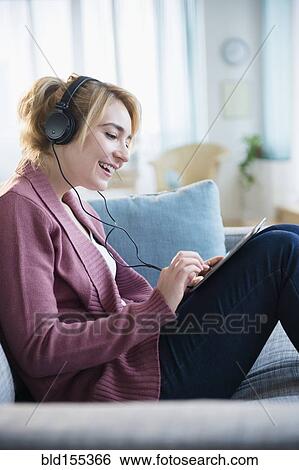 Stock Photograph - Caucasian woman listening to headphones and digital tablet. Fotosearch