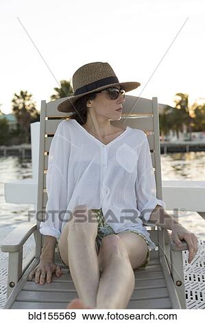 Stock Photo - Caucasian woman relaxing in deck chair. Fotosearch