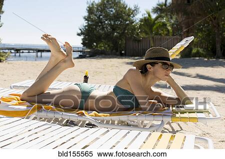 Stock Photography - Caucasian woman relaxing on beach. Fotosearch