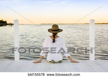 Caucasian woman sitting at edge of pier View Large Photo Image Stock Photo - Caucasian woman sitting at edge of pier. Fotosearch