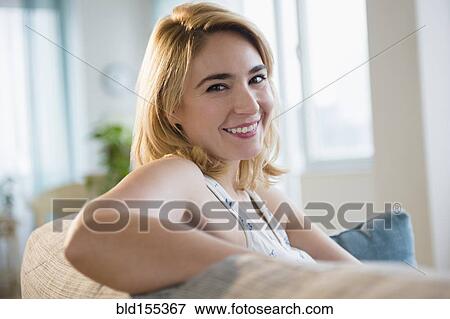 Stock Photo - Caucasian woman smiling on sofa. Fotosearch