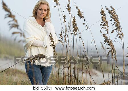 Caucasian woman standing in tall grass on beach View Large Photo Image Stock Image - Caucasian woman standing in tall grass on beach. Fotosearch