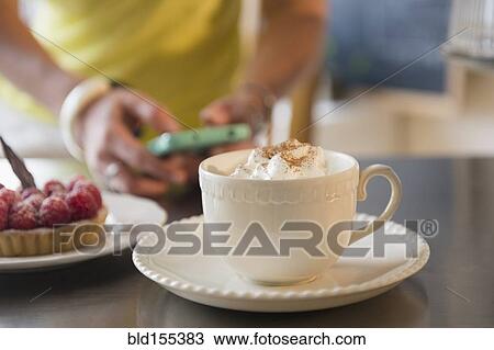 Stock Image - Caucasian woman using cell phone at cafe. Fotosearch