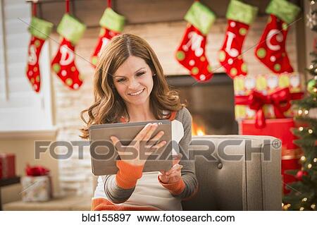 Stock Photo - Caucasian woman using digital tablet at Christmas. Fotosearch