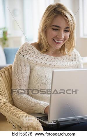 Caucasian woman using laptop in armchair View Large Photo Image Stock Photo - Caucasian woman using laptop in armchair. Fotosearch
