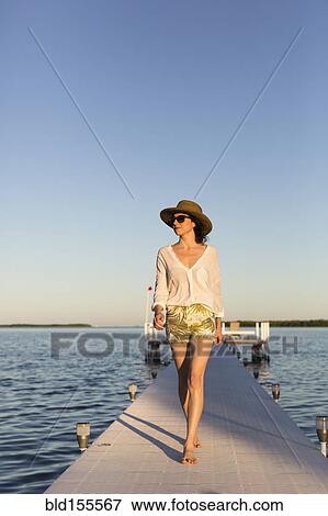 Stock Photo - Caucasian woman walking on pier over water. Fotosearch