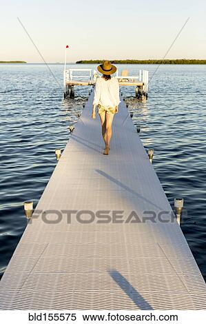 Caucasian woman walking on pier over water View Large Photo Image Stock Photography - Caucasian woman walking on pier over water. Fotosearch