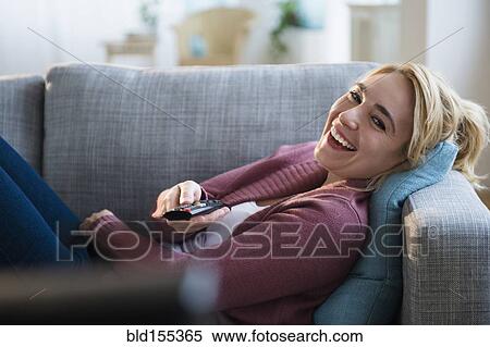 Stock Photography - Caucasian woman watching television on sofa. Fotosearch