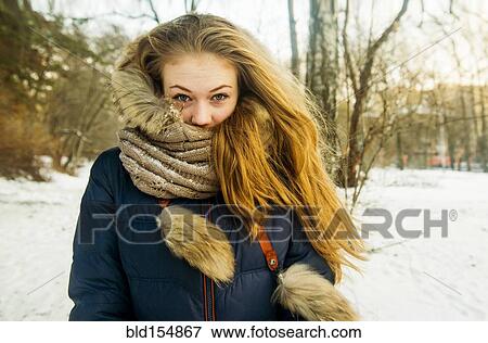 Stock Photo - Caucasian woman wearing fur hood and coat in snowy field. Fotosearch