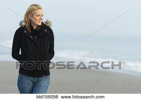 Stock Photograph - Caucasian woman wearing jacket on beach. Fotosearch