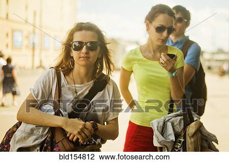 Stock Image - Caucasian women carrying bags outdoors. Fotosearch