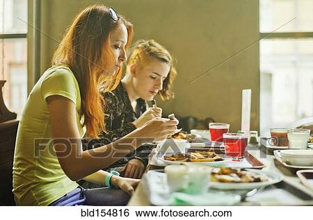 Stock Photograph - Caucasian women eating in dining room. Fotosearch