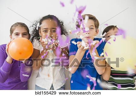 Stock Photo - Children blowing party confetti and balloons. Fotosearch