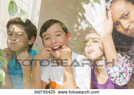 Children making faces behind window View Large Photo Image Stock Photography - Children making faces behind window. Fotosearch