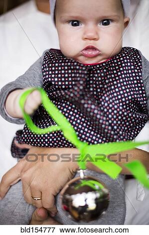 Close up of Caucasian baby girl holding Christmas ornament View Large Photo Image Stock Photo - Close up of Caucasian baby girl holding Christmas ornament. Fotosearch