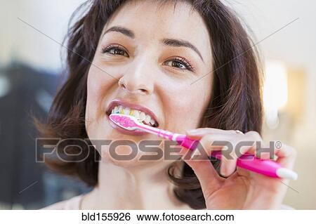 Stock Photograph - Close up of Hispanic woman brushing her teeth. Fotosearch