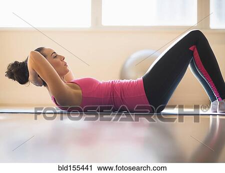 Stock Image - Close up of Hispanic woman doing sit-ups in gym. Fotosearch