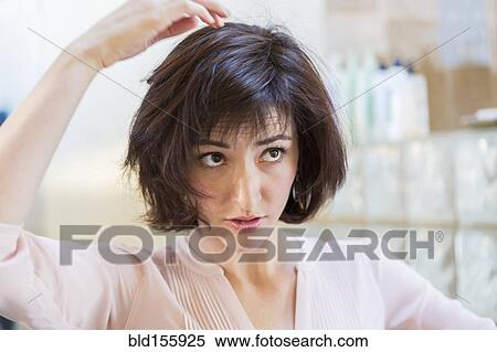 Stock Photography - Close up of Hispanic woman examining her hair. Fotosearch