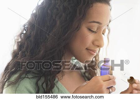 Stock Photograph - Close up of mixed race woman smelling aromatherapy oil. Fotosearch