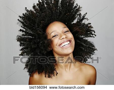 Picture - Close up of mixed race woman tossing curly hair. Fotosearch