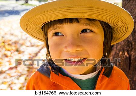 Stock Photograph - Close up of smiling mixed race boy wearing sun hat. Fotosearch