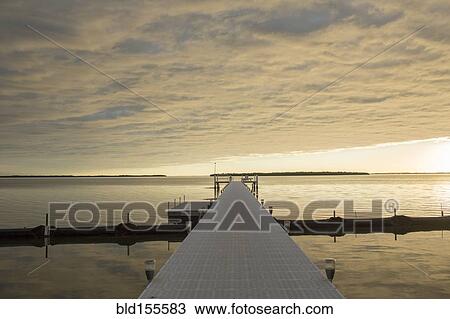 Stock Image - Clouds in sky over pier and ocean. Fotosearch