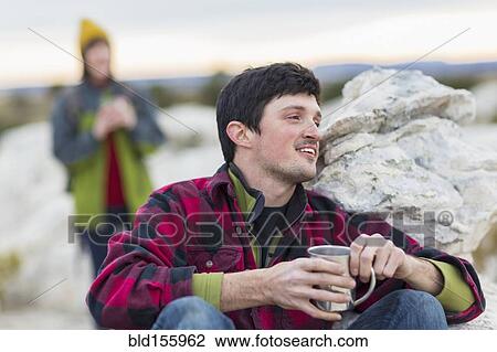 Stock Image - Couple drinking coffee on rock formations. Fotosearch