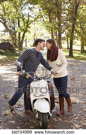 Couple kissing over scooter in suburban neighborhood View Large Photo Image Stock Photo - Couple kissing over scooter in suburban neighborhood. Fotosearch