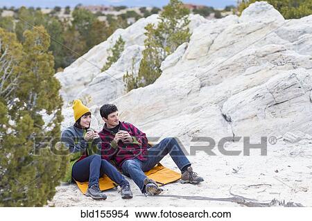 Picture - Couple sharing coffee on rock formations. Fotosearch