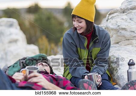 Stock Photo - Couple sharing coffee on rock formations. Fotosearch