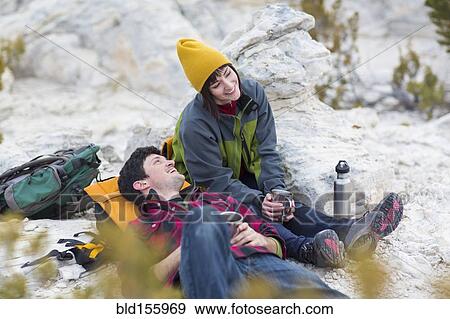 Stock Photo - Couple sharing coffee on rock formations. Fotosearch