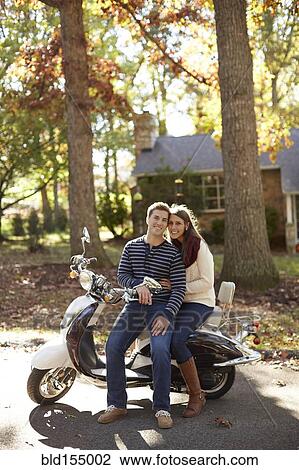 Couple sitting on scooter in suburban neighborhood View Large Photo Image Stock Image - Couple sitting on scooter in suburban neighborhood. Fotosearch